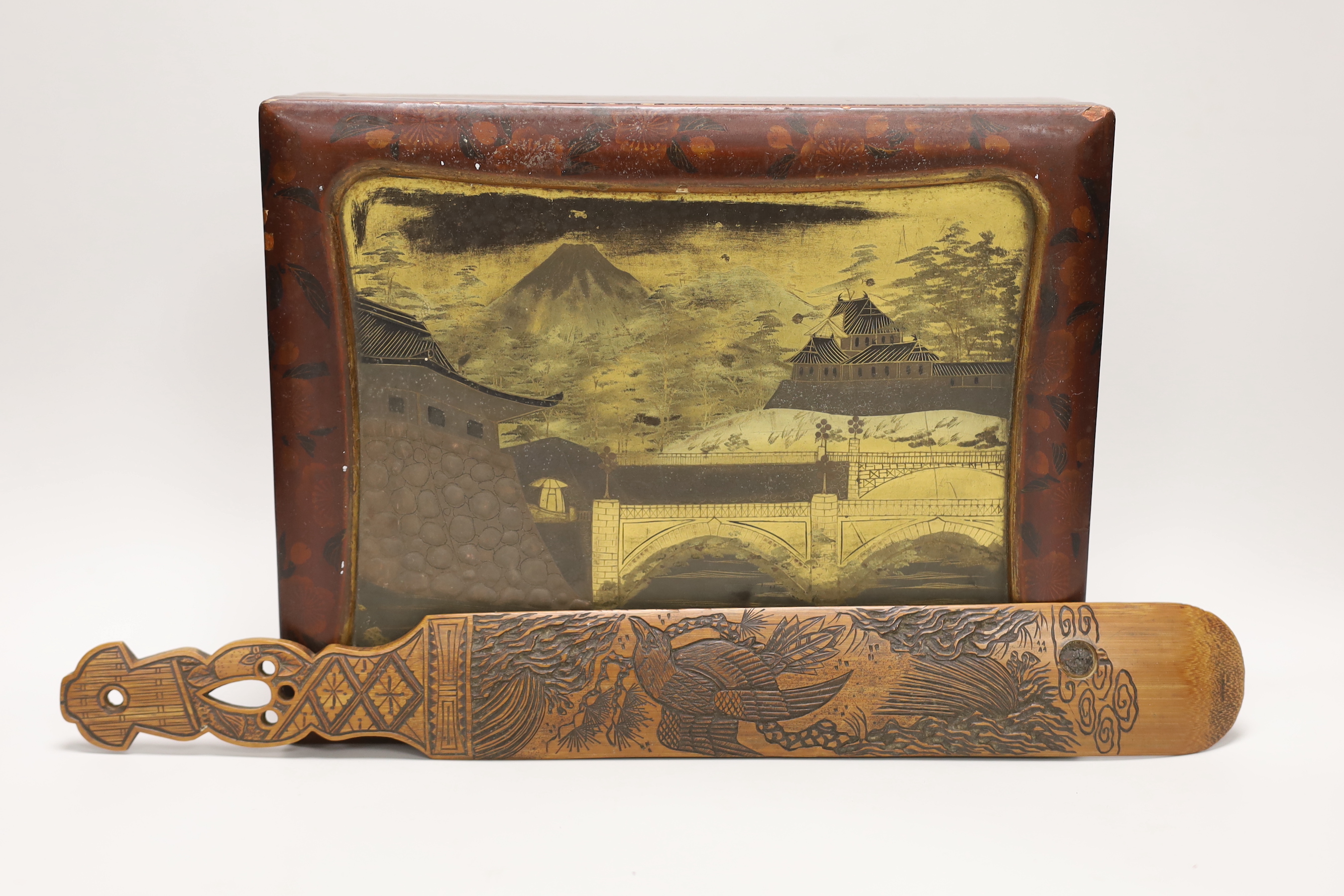A Japanese lacquer games box, the cover having a central landscape painting together with a carved bamboo page turner, box 30 cm wide x 24 deep